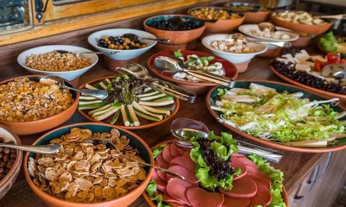 Açık büfe anlayışı aslında yüzyıllar öncesine dayanan bir paylaşım kültürünün modern yansımasıdır. İnsanlar topluluk halinde yemek yerken, farklı seçenekler sunma geleneği tarih boyunca birçok toplumda görülmüştür. Özellikle Osmanlı’da ziyafet sofraları, Avrupa’da ise şölenler bu anlayışın temellerini oluşturmuştur. Günümüzde ise otellerden restoranlara, davetlerden kutlamalara kadar pek çok alanda açık büfe yaygın olarak tercih edilmektedir. Konulu bir haber görseli.