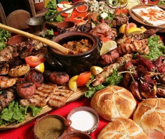 Bulgar mutfağı, tarih boyunca farklı kültürlerin etkisi altında şekillenmiş zengin bir yemek geleneğine sahiptir. Osmanlı, Bizans ve Balkan kültürlerinin birleşimi, Bulgar mutfağını eşsiz kılan temel unsurlardan biridir. Bulgar yemekleri, genellikle taze sebze, yoğurt ve peynir gibi doğal ürünlerle hazırlanır. Sofralarda sıkça yer alan tarator ve banitsa, bu mutfağın en bilinen lezzetlerindendir. Tarator, soğuk yoğurt çorbası olarak yaz aylarında tercih edilirken, banitsa börek çeşidi olarak kahvaltıların vazgeçilmezidir. Konulu bir haber görseli.