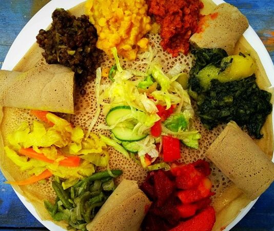 Etiyopya mutfağı, Afrika’nın doğusunda yer alan bu kadim ülkenin kültürel mirasını yansıtan eşsiz bir gastronomi deneyimi sunar. Bu mutfak, yüzyıllar boyunca farklı kültürlerin ve yerel geleneklerin bir araya gelmesiyle şekillenmiştir. Baharatlar, tahıllar ve sebzelerin yoğun kullanımı, Etiyopya yemeklerini hem lezzetli hem de besleyici kılar. Ülkenin farklı bölgelerinde yetişen malzemeler, yemeklerin her birine kendine özgü bir karakter kazandırır. Bu nedenle Etiyopya yemekleri, hem yerel halk hem de turistler tarafından büyük ilgi görmektedir. Konulu bir haber görseli.