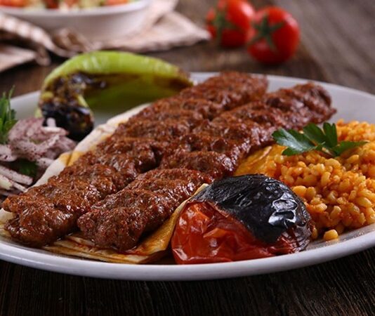 Kebabın Farklı Yüzleri Anadolu’dan Dünyaya Açılan Ateşin Hikâyesi Kebap, Türk mutfağının en köklü ve en tanınan lezzetlerinden biri olarak, yalnızca bir yemek değil aynı zamanda bir yaşam biçimi olarak da değerlendirilebilir. Etin ateşle buluştuğu bu eşsiz teknik, binlerce yıllık geçmişe sahiptir ve tarih boyunca birçok uygarlığın mutfağında kendine yer bulmuştur. Ancak Anadolu toprakları, kebap kültürünü sadece korumakla kalmamış, aynı zamanda onu çeşitlendirip zenginleştirmiştir. Konulu bir haber görseli.