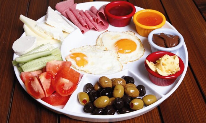 Türk mutfağında kahvaltı yalnızca güne başlamak için yapılan bir öğün değil, aynı zamanda kültürel bir gelenektir. Tarih boyunca ailelerin bir araya geldiği, dostların sohbet eşliğinde vakit geçirdiği sofraların baş tacı olmuştur. Özellikle pazar günleri kurulan geniş kahvaltı sofraları, hem çeşitliliğiyle hem de paylaşımın verdiği mutlulukla öne çıkar. Konulu bir haber görseli.