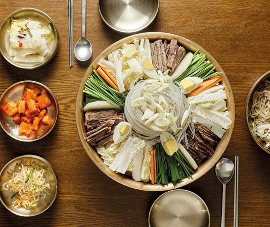 Kuzey Kore mutfağı, Kore Yarımadası’nın kadim yemek kültürünün önemli bir parçası olarak dikkat çeker. Bu mutfak, tarih boyunca bölgenin iklimi, tarım ürünleri ve toplumsal yapısıyla şekillenmiş ve kendine özgü bir gastronomi anlayışı oluşturmuştur. Siyasi yapısından dolayı dış dünyaya çok açık olmayan Kuzey Kore, yemek kültürü bakımından yine de oldukça zengin ve köklü bir mirasa sahiptir. Geleneksel yemekler, hem kırsal yaşamın etkilerini hem de bölgenin tarihsel bağlarını yansıtır. Özellikle fermente ürünler, sebze çeşitleri, tahıllar ve yerel baharatlar mutfağın temel taşlarını oluşturur. Konulu bir haber görseli.