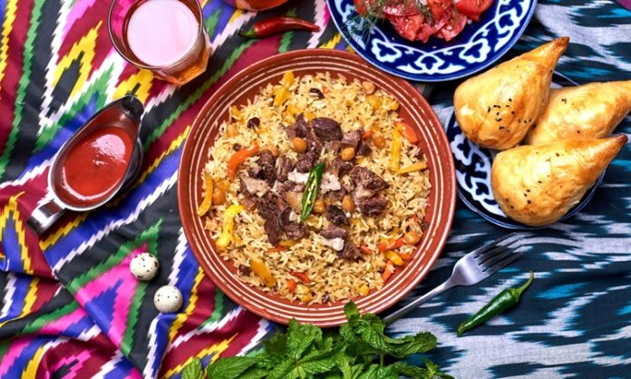 Özbekistan mutfağı, Orta Asya’nın bereketli topraklarında, tarih boyunca farklı kültürlerin etkisiyle şekillenmiş zengin bir gastronomi mirasına sahiptir. İpek Yolu’nun kesişim noktalarından biri olan Özbekistan, hem Doğu hem de Batı mutfak geleneklerini harmanlamış, yemek kültürünü çeşitlendirmiştir. Et ve tahıllar, mutfağın temelini oluştururken; baharatlar ve taze sebzeler, yemeklere özgün tat ve aroma kazandırır. Konulu bir haber görseli.