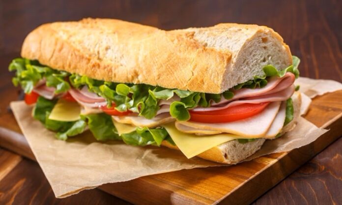 Günlük hayatın vazgeçilmez atıştırmalıkları arasında yer alan sandviç, hem pratik hazırlanışı hem de sınırsız malzeme kombinasyonlarıyla dünya mutfağında önemli bir yere sahiptir. Kahvaltıdan öğle yemeğine, akşam atıştırmalıklarından gece kaçamaklarına kadar günün her anına uyum sağlayan bu lezzet, kültürden kültüre farklı yorumlarla sofralarda yer bulur. Konulu bir haber görseli.