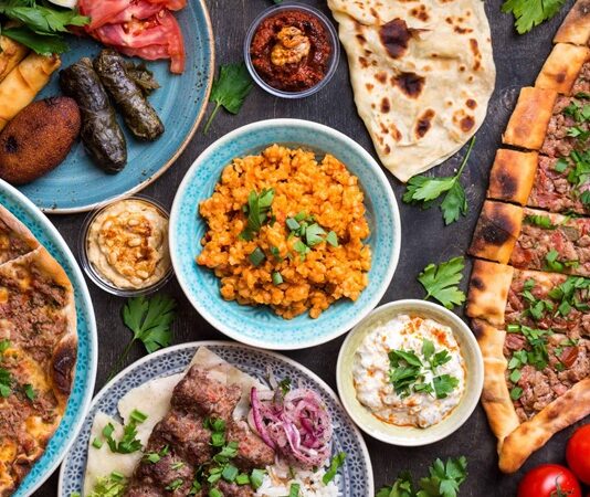 Şark köşesi denildiğinde akla yalnızca geleneksel oturma düzeni gelmez; aynı zamanda Anadolu’nun binbir çeşit yöresel lezzetinin sunulduğu, samimi ve kültürel dokuyu yansıtan sofralar da hatırlanır. Yüzyıllardır Anadolu mutfağının bir parçası olan bu sofralar, hem görsel hem de damak tadı açısından zengin bir deneyim sunar. Ahşap sedirler, el dokuması kilimler ve bakır işlemeli tepsiler eşliğinde sunulan yöresel yemekler, misafirperverliğin en güzel örneklerinden biridir. Konulu bir haber görseli.