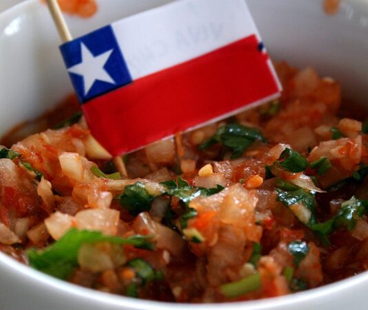 Şili mutfağı, Güney Amerika’nın batı kıyısında uzanan bu uzun ve dar ülkenin zengin coğrafi yapısının bir yansımasıdır. Pasifik Okyanusu’ndan And Dağları’na kadar uzanan geniş bir alanda şekillenen mutfak kültürü, hem deniz ürünleri hem de kara mahsulleri açısından büyük bir çeşitlilik sunar. Ülkenin farklı bölgelerinde kullanılan malzemeler ve pişirme yöntemleri, Şili’nin tarih boyunca farklı kültürlerden aldığı etkileri ortaya koyar. Konulu bir haber görseli.