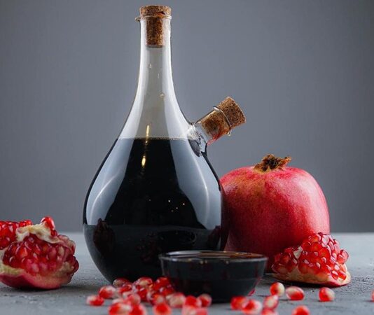 Nar ekşisi, yüzyıllardır Türk mutfağının vazgeçilmez tatlandırıcılarından biri olarak sofralarda yerini alıyor. Yoğun kıvamı, hafif ekşi ve tatlı aromasıyla yemeklere derin bir lezzet katan bu ürün, sadece damak tadına değil, aynı zamanda sağlığa olan faydalarıyla da öne çıkıyor. Anadolu’nun birçok bölgesinde ev yapımı olarak üretilen nar ekşisi, günümüzde endüstriyel üretimle de geniş kitlelere ulaşıyor. Geleneksel yöntemlerle hazırlanan, katkısız ve doğal olan çeşitleri ise her zaman en çok tercih edilenler arasında. Doğal nar ekşisi üretiminde yalnızca taze nar taneleri kullanılıyor. Meyve suyu çıkarıldıktan sonra uzun süre kısık ateşte kaynatılarak koyu kıvama getiriliyor. Bu zahmetli süreç, hem lezzetin yoğunlaşmasını hem de narın şifa dolu özelliklerinin korunmasını sağlıyor. Özellikle kış aylarında salatalardan et yemeklerine kadar pek çok tarifte kullanılan nar ekşisi, sofralara hem renk hem de tat katıyor. Konulu bir haber görseli.