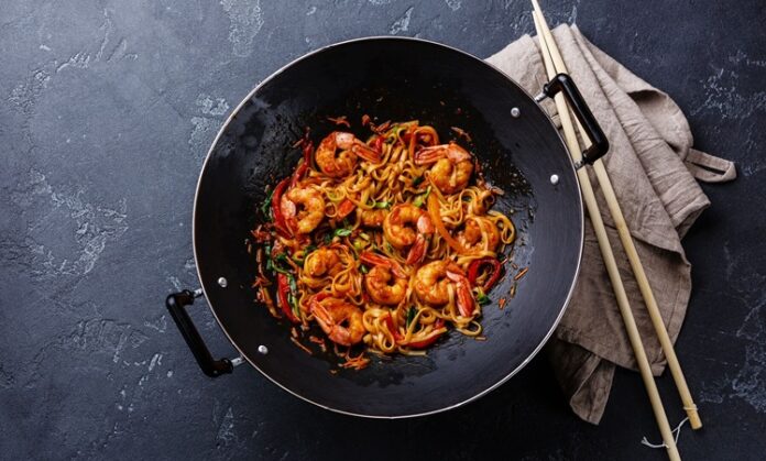 Woklama, kökeni Çin mutfağına dayanan ve asırlardır kullanılan bir pişirme tekniğidir. Yüksek ateş ve özel tasarlanmış derin tavalarda yapılan bu yöntem, kısa sürede yüksek ısı ile yemeklerin hazırlanmasını sağlar. Bu teknik, sadece hız değil aynı zamanda malzemelerin tazeliğini ve besin değerini korumasıyla da öne çıkar. Özellikle sebzelerin parlak rengini, etlerin ise sulu dokusunu koruyabilmesi, woklamanın diğer pişirme yöntemlerinden ayrılmasını sağlar. Konulu bir haber görseli.