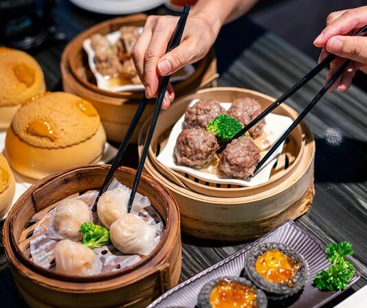 Dim Sum, Çin mutfağının en köklü ve sevilen geleneklerinden biridir. Çay kültürüyle özdeşleşen bu yemek türü, küçük porsiyonlar halinde servis edilen çeşitli yiyeceklerden oluşur. Tarihi, yüzyıllar öncesine dayanan bu lezzet, özellikle Guangdong bölgesinde ortaya çıkmış ve zamanla Çin’in farklı bölgelerine yayılmıştır. Yolculara hızlı ve doyurucu yiyecek sunma amacıyla başlayan bu gelenek, bugün hem Çin mutfağının hem de dünya gastronomisinin vazgeçilmez bir parçası haline gelmiştir. Konulu bir haber görseli.