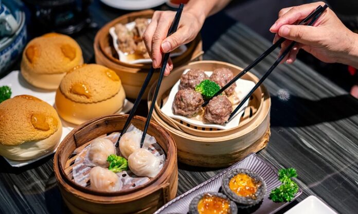 Dim Sum, Çin mutfağının en köklü ve sevilen geleneklerinden biridir. Çay kültürüyle özdeşleşen bu yemek türü, küçük porsiyonlar halinde servis edilen çeşitli yiyeceklerden oluşur. Tarihi, yüzyıllar öncesine dayanan bu lezzet, özellikle Guangdong bölgesinde ortaya çıkmış ve zamanla Çin’in farklı bölgelerine yayılmıştır. Yolculara hızlı ve doyurucu yiyecek sunma amacıyla başlayan bu gelenek, bugün hem Çin mutfağının hem de dünya gastronomisinin vazgeçilmez bir parçası haline gelmiştir. Konulu bir haber görseli.