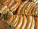 Ispanaklı börek, hem kahvaltı sofralarının hem de özel davetlerin vazgeçilmez lezzetlerinden biridir. İncecik açılmış yufkaların arasında yer alan ıspanak, böreğe hem doğal bir renk hem de zengin bir besin değeri katar. Ispanaklı börek, özellikle ev yapımı olduğunda, hem lezzet hem de sağlık açısından sofralara değer katar. Bu yazımızda ıspanaklı böreğin tarihçesinden malzeme seçimlerine, hazırlık aşamalarından pişirme tekniklerine kadar detaylı bilgiler bulabilirsiniz. Konulu bir haber görseli.