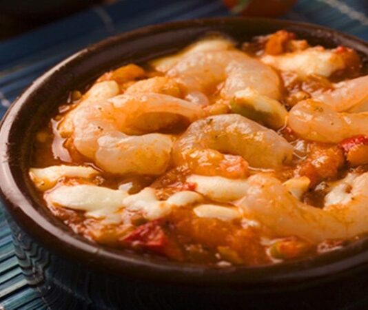 Karides güveç, taze karideslerin sebzeler, aromatik baharatlar ve zeytinyağıyla birlikte güveçte pişirilmesiyle hazırlanan, hem sağlıklı hem de lezzetli bir deniz ürünü yemeğidir. Bu yöntem, karidesin doğal lezzetini korumasına ve sebzelerle aromalarının birbirine geçmesine olanak sağlar. Özellikle hafif öğünler arayanlar için ideal bir seçenektir. Konulu bir haber görseli.