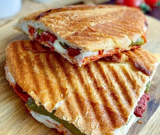 Karışık Tost: Kahvaltıdan Öğleye Pratik Lezzet Karışık tost, özellikle Türkiye’de sabah kahvaltılarının ve ara öğünlerin vazgeçilmez lezzetlerinden biri haline gelmiştir. Bu tost çeşidi, klasik kaşarlı tostun ötesine geçerek sucuk, salam, domates, biber ve peynir gibi malzemelerin bir araya gelmesiyle hazırlanır. Böylece hem doyurucu hem de zengin bir lezzet sunar. Konulu bir haber görseli.