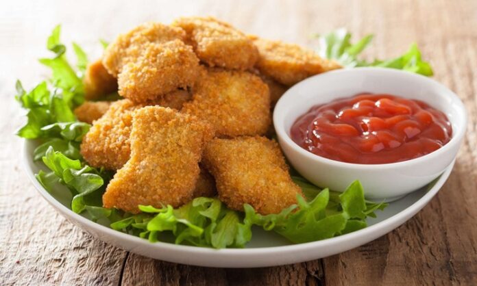 Nugget, özellikle hızlı ve pratik öğün arayanların favori seçeneklerinden biri haline gelmiş bir yiyecektir. Kökeni Amerika’ya dayanan bu atıştırmalık, 1950’li yıllarda geliştirilmiş ve kısa sürede dünya çapında popüler olmuştur. Tavuk eti, kaplamalı ve kızartılmış olarak hazırlanarak altın sarısı bir dış yüzeye kavuşur. Konulu bir haber görseli.