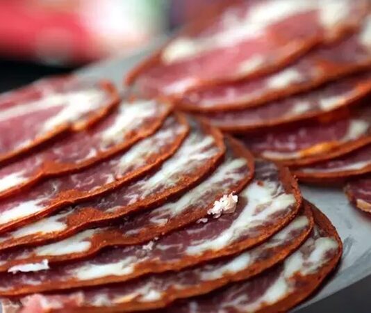 Pastırma dilimi, Türk mutfağının köklü geleneklerinden günümüze taşınmış, eşsiz aroması ve yoğun lezzetiyle sofralarda özel bir yere sahip olan bir üründür. Kayseri başta olmak üzere Anadolu’nun farklı bölgelerinde üretilen pastırma, ince dilimlenerek tüketildiğinde hem kahvaltılarda hem de yemeklerde ayrı bir tat sunar. Yüzyıllardır varlığını koruyan bu özel lezzet, günümüzde de sofraların en çok aranan ürünleri arasında yer almaktadır. Konulu bir haber görseli.