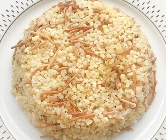 Şehriyeli pilav, Türk mutfağının en klasik ve sevilen yemeklerinden biridir. Tarih boyunca Osmanlı mutfağından günümüz sofralarına kadar uzanan bir lezzet yolculuğuna sahiptir. Küçük pirinç taneleri ve kavrulmuş şehriyelerin birleşimi, pilava hem doku hem de aroma kazandırır. Konulu bir haber görseli.