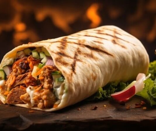 Orta Doğu mutfağının en bilinen sokak lezzetlerinden biri olan Shawarma, ince dilimlenmiş etin özel baharatlarla marine edilip dikey döner üzerinde pişirilmesiyle hazırlanır. Genellikle tavuk, dana veya kuzu eti kullanılır ve lavaş veya pita ekmeğiyle servis edilir. Bu lezzet, hem hızlı hem de doyurucu bir öğün alternatifi sunar. Konulu bir haber görseli.