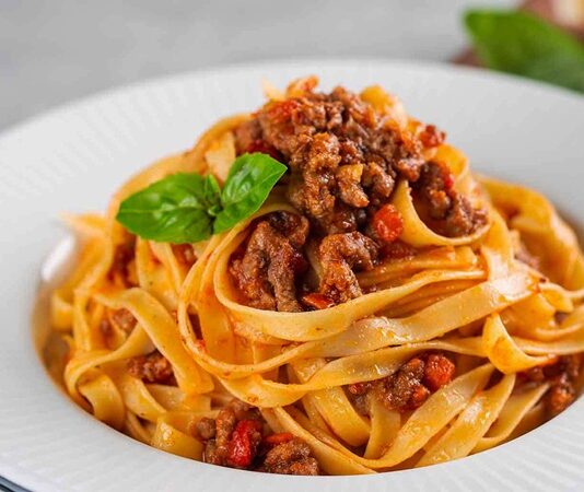 Tagliatelle, İtalyan mutfağının en tanınmış makarna çeşitlerinden biri olarak bilinir. Genellikle geniş ve uzun şeritler halinde hazırlanır. Bu makarna türü, özellikle Bolognese sosu ile eşsiz bir uyum yakalar ve İtalya’nın Emilia-Romagna bölgesinde köklü bir geçmişe sahiptir. Konulu bir haber görseli.