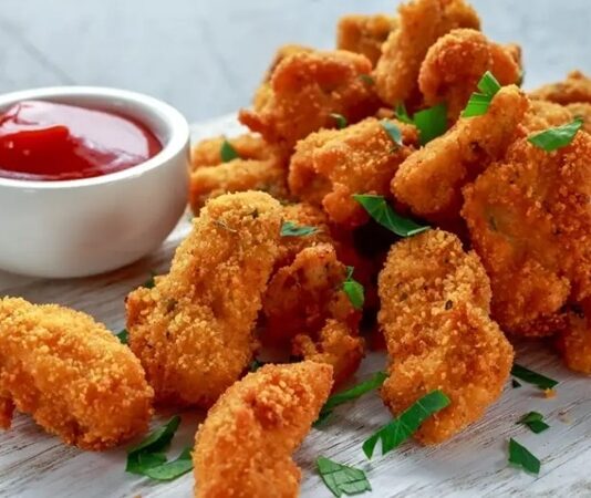 Tavuk nugget, hem çocuklar hem de yetişkinler tarafından çok sevilen bir atıştırmalıktır. Altın rengi çıtır kaplaması ve yumuşak tavuk eti ile mükemmel bir uyum sağlayan nugget, evde veya restoranlarda kolayca hazırlanabilir. Özellikle hızlı atıştırmalık olarak tercih edilen bu lezzet, farklı soslar ile birlikte sunulduğunda sofralara renk katar. Bugün tavuk nugget’in tarihçesinden hazırlama tekniklerine, pişirme yöntemlerinden sunum önerilerine kadar detaylı bir inceleme yapacağız. Konulu bir haber görseli.