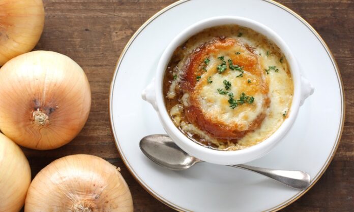 Dünya mutfağının en etkileyici ve simgesel lezzetlerinden biri olan Fransız soğan çorbası, hem Fransa’nın hem de küresel gastronomi dünyasının vazgeçilmezlerinden biri hâline gelmiştir. Orta Çağ’dan bu yana Fransız halk mutfağında kendine yer bulan bu çorba, zamanla uluslararası arenada da tanınmış ve birçok ülkenin restoran menülerinde yer almaya başlamıştır. Sade bir malzeme listesine sahip gibi görünen Fransız soğan çorbası, karamelize soğan, et suyu ve üzerine eklenen peynirli ekmek ile zenginleşerek hem doyurucu hem de aromatik bir deneyim sunar. Konulu bir haber görseli.