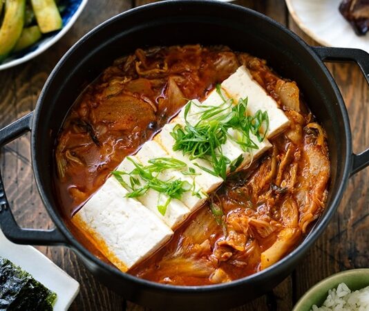 Güney Kore mutfağının en ikonik çorbalarından biri olan Kimchi Jjigae, son yıllarda dünya genelinde hem restoran menülerinde hem de ev yapımı tariflerde popülerliğini artırıyor. Özellikle fermente lahana, baharatlı biber ve dengeli et suyu ile hazırlanan bu çorba, hem doyurucu hem de sağlık açısından zengin bir yemek olarak öne çıkıyor. Türkiye’de de gastronomi meraklılarının ilgisini çeken Kimchi Jjigae, Kore mutfağının globalleşmesinde önemli bir rol oynuyor. Lezzeti ve besleyici özellikleri sayesinde çorba severler için hem geleneksel hem de modern alternatifler sunuyor. Konulu bir haber görseli.