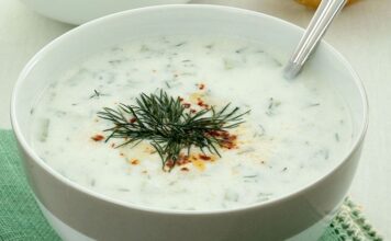 Cacık, Türk mutfağının en sevilen ve ferahlatıcı tariflerinden biri olarak öne çıkıyor. Özellikle yaz aylarında sofraları süsleyen bu yoğurt bazlı karışım, hem hafif hem de besleyici bir seçenek olarak dikkat çekiyor. Cacık hem öğle yemeklerinin yanında hem de akşam yemeklerinde meze olarak sunulabiliyor. Taze nane, salatalık ve sarımsak gibi malzemelerle hazırlanan cacık, sağlıklı ve lezzetli oluşuyla mutfakların vazgeçilmezi haline geliyor. Konulu bir haber görseli.