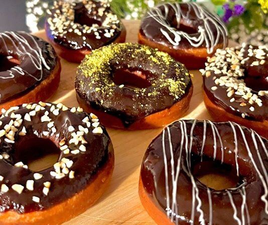 Dünyanın en sevilen tatlılarından biri olan donut, günümüzde yalnızca klasik şekerli halka formundan ibaret değil. Renkli glazeler, çikolata kaplamalar, meyve aromaları ve hatta tuzlu versiyonlarıyla karşımıza çıkan bu tatlı, hem çocukların hem yetişkinlerin ilgisini çekmeye devam ediyor. Özellikle kafe zincirlerinin yaygınlaşmasıyla birlikte donut tercih eden kitlenin her geçen gün arttığı görülüyor. Görsel sunumdaki çeşitlilik, tatlının sosyal medya platformlarında hızla viral olmasına yardımcı oluyor. Konulu bir haber görseli.