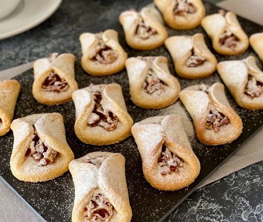 Türkiye’nin en geleneksel tatlılarından biri olan Elmalı Kurabiye, son dönemlerde ev yapımı tariflerin popülerleşmesiyle yeniden gündeme geldi. Özellikle kış mevsiminin gelmesiyle birlikte sıcak çay ve kahve eşlikçisi olarak tercih edilen bu kurabiye, hem hafif dokusu hem de tarçınla birleşen elma aroması sayesinde tekrar ilgi odağı hâline geldi. Son yıllarda sosyal medya platformlarında paylaşılan tarif videolarının etkisiyle Elmalı Kurabiye, genç kuşak arasında da popüler bir ev tatlısı hâline dönüşüyor. Konulu bir haber görseli.