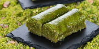 Fıstıklı Sarma Tatlısının Osmanlı’dan Günümüze Uzanan Lezzet Yolculuğu Fıstıklı sarma, Türk tatlı kültürünün hem tarihsel hem damak zevki açısından en özel lezzetlerinden biri olarak biliniyor. Osmanlı saray mutfağından günümüze taşınan zengin mirasın bir parçası olan bu tatlı, özellikle özel günlerde, bayram sofralarında ve davet masalarında sıklıkla tercih ediliyor. Bu nedenle sadece gastronomik bir tatlı olmakla kalmayan fıstıklı sarma, kültürel bir simge haline gelmiş durumda. Şerbetli tatlılar arasında kendine özgü yapısıyla farklı bir yer edinen bu lezzet, hem yapımı hem sunumu hem de ustalığıyla dikkat çekiyor. Konulu bir haber görseli.