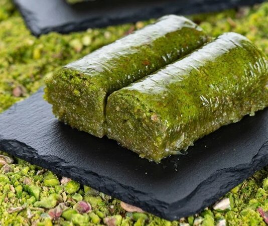 Fıstıklı sarma, Türk tatlı kültürünün hem tarihsel hem damak zevki açısından en özel lezzetlerinden biri olarak biliniyor. Osmanlı saray mutfağından günümüze taşınan zengin mirasın bir parçası olan bu tatlı, özellikle özel günlerde, bayram sofralarında ve davet masalarında sıklıkla tercih ediliyor. Bu nedenle sadece gastronomik bir tatlı olmakla kalmayan fıstıklı sarma, kültürel bir simge haline gelmiş durumda. Şerbetli tatlılar arasında kendine özgü yapısıyla farklı bir yer edinen bu lezzet, hem yapımı hem sunumu hem de ustalığıyla dikkat çekiyor. Konulu bir haber görseli.