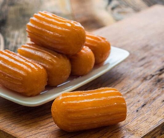 Türk mutfağının en sevilen şerbetli tatlılarından biri olan kemalpaşa, yıllardır hem ev sofralarında hem de restoranlarda kendine özel bir yer edinen köklü bir lezzet olarak dikkat çekiyor. Özellikle pratik hazırlanışı ve hafif dokusu sayesinde geniş kitlelere hitap eden bu tatlı, günümüzde yeniden yükselen popülaritesiyle gastronomi dünyasında adından sıkça söz ettiriyor. Hamurunun yoğun olmaması, şerbeti dengeli şekilde içine çekmesi ve yumuşacık kıvamıyla damakta iz bırakan kemalpaşa tatlısı, modern sunum trendlerine uyum sağlayarak geleneksel olmaktan çıkmadan yenilikleri de kucaklıyor. Konulu bir haber görseli.