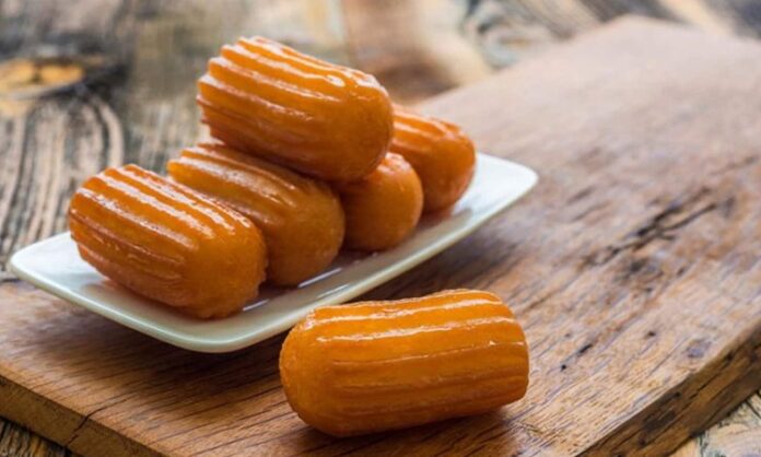 Türk mutfağının en sevilen şerbetli tatlılarından biri olan kemalpaşa, yıllardır hem ev sofralarında hem de restoranlarda kendine özel bir yer edinen köklü bir lezzet olarak dikkat çekiyor. Özellikle pratik hazırlanışı ve hafif dokusu sayesinde geniş kitlelere hitap eden bu tatlı, günümüzde yeniden yükselen popülaritesiyle gastronomi dünyasında adından sıkça söz ettiriyor. Hamurunun yoğun olmaması, şerbeti dengeli şekilde içine çekmesi ve yumuşacık kıvamıyla damakta iz bırakan kemalpaşa tatlısı, modern sunum trendlerine uyum sağlayarak geleneksel olmaktan çıkmadan yenilikleri de kucaklıyor. Konulu bir haber görseli.