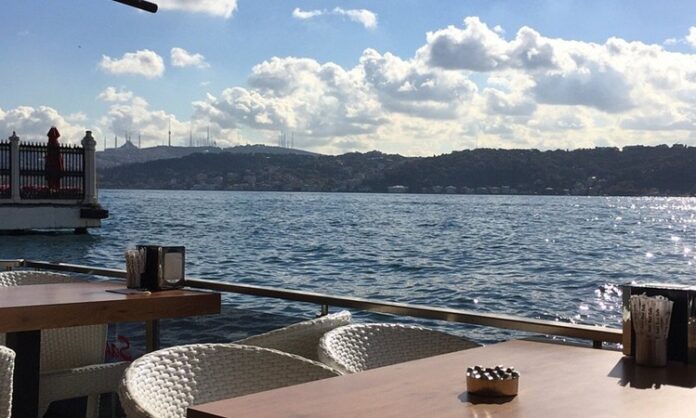 Şehir hayatının yoğun temposu içinde denizle temas edilebilen nadir alanlardan biri olan sahil kafeleri, son yıllarda hem yerel halkın hem de ziyaretçilerin en çok tercih ettiği mekânlar arasında yer alıyor. Denizin sesi, açık hava ferahlığı ve manzara eşliğinde sunulan yeme içme deneyimi, sahil kafelerini sıradan kafelerden ayıran en önemli unsur olarak öne çıkıyor. Bu mekânlar, sadece bir şeyler içilen alanlar değil; aynı zamanda şehirden kaçışın en kolay yollarından biri hâline geliyor. Konulu bir haber görseli.